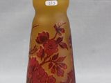 a glass vase with red flowers on it on a white surface