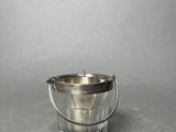 a silver bucket with a handle sitting on a table