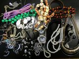 many different necklaces and bracelets laid out on a table