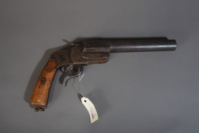 un vieux pistolet muni d'une étiquette, posé sur une surface grise
