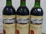 trois bouteilles de vin rouge posées sur une table en bois