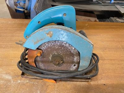 une scie circulaire bleue posée sur une table en bois