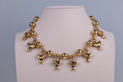 a close up of a gold necklace on a mannequin mannequin