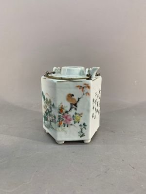 a small vase with a bird on it on a table