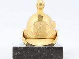 an image of a gold bell on a black marble base