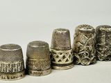 several antique thimbles are lined up in a row on a white surface