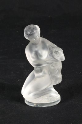une figurine en verre représentant un homme à genoux sur une surface noire