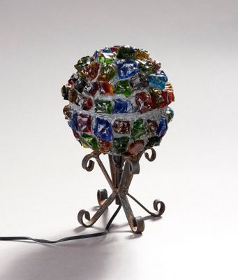 une boule de verre posée sur un socle métallique, sur une surface blanche