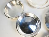 quatre plats en argent posés sur une table blanche, avec des couvercles en argent