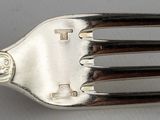 a silver fork with a cross on it sitting on a table