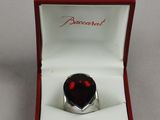 an image of a ring in a box with a red stone