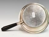 a silver pan with a black handle on a white surface