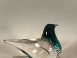 a glass bird sitting on top of a glass bowl