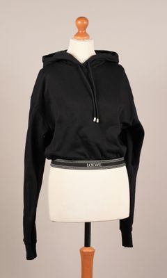 un sweat à capuche noir sur un mannequin portant une jupe blanche