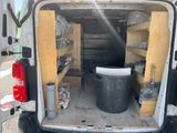 the back of a van with the door open and a trash can in the back