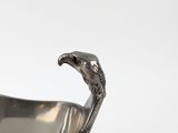 a silver plate with a bird on it on a saucer
