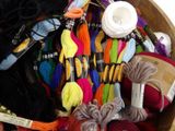 a wooden bowl filled with different colored threads
