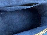 the inside of a blue purse with gold zippers