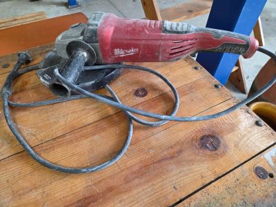 a red and black electric drill on a wooden table