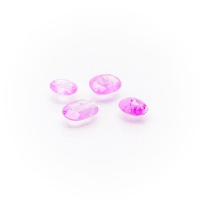 a group of three pink gems sitting on top of a white surface