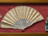 trois éventails en papier disposés en forme d'éventail dans un cadre en bois sur fond rouge