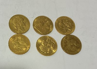 six gold sovereigns, one of which is a sovereign, are on a white surface
