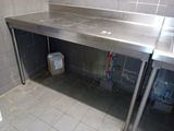 a stainless steel counter with a sink and a trash can