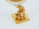 a gold plate with a glass bowl on top of it