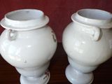 two white vases that are sitting on a table