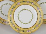 three yellow and white plates with pink flowers on them on a white surface