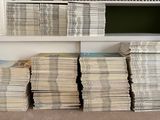 many stacks of newspapers stacked on a shelf in a room
