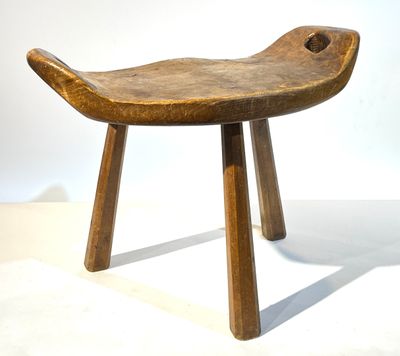 un petit tabouret en bois à deux pieds posé sur une surface blanche