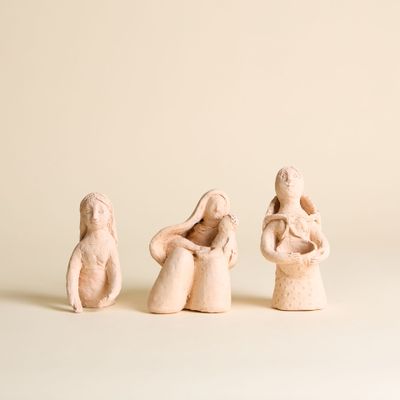 trois petites figurines représentant des personnes assises sur une surface blanche
