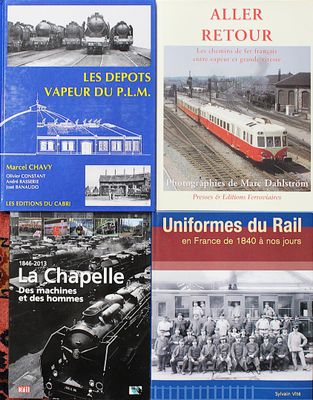 plusieurs livres posés sur une table, avec un train en arrière-plan