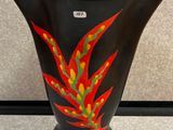 un vase noir orné d'une fleur rouge et jaune