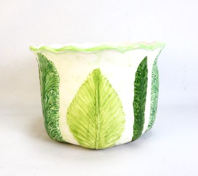 a green and white planter with leaves on it