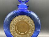 une image représentant une bouteille en verre bleue sur laquelle repose une pièce d'or