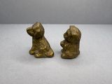une paire de figurines de chiens en laiton posées sur une surface blanche