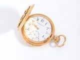 a gold pocket watch sitting on a white surface