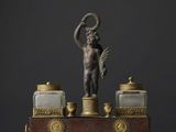 une figurine antique en bronze représentant un Cupidon tenant une couronne
