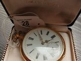 une petite montre de poche en or, dans un écrin posé sur une table
