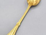 a gold spoon with a long handle sitting on top of a table