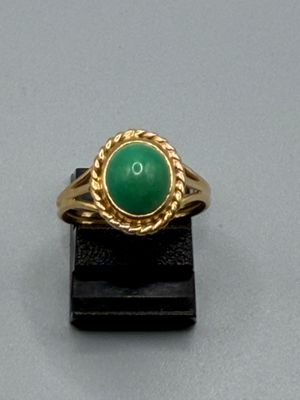 une image d'une bague en or avec une pierre verte au centre