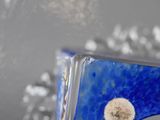 a blue glass vase with a dandelion in it