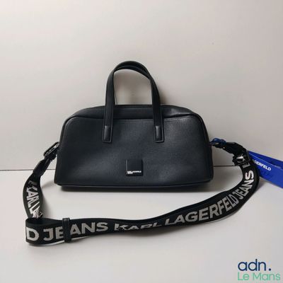 Le sac à main noir est posé sur la table, avec une lanière qui l'entoure.