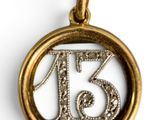 a close up of a gold pendant with the number thirteen on it
