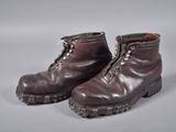une paire de bottes en cuir marron à lacets posées sur une surface grise