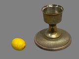 a silver cup next to a lemon on a gray surface
