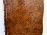 un vieux livre à la couverture marron posé sur une table blanche