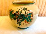 un vase blanc orné d'un motif vert et jaune